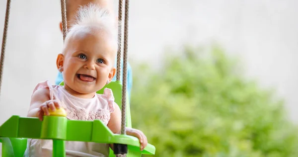 Fröhliches, fröhliches Baby, das auf der Schaukel lächelt — Stockfoto