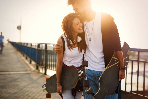 Imagen de pareja joven y atractiva que lleva monopatines —  Fotos de Stock