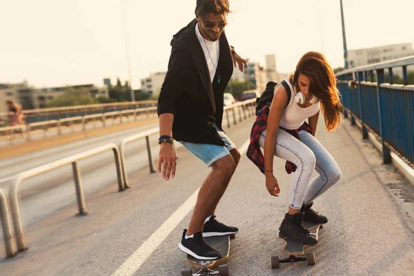 Jovem casal atraente andar de skate e se divertindo — Fotografia de Stock