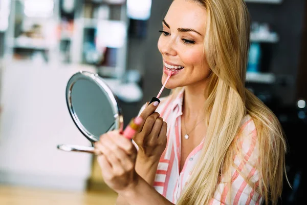 Молодая красивая женщина наносит макияж с помощью маленького зеркала — стоковое фото