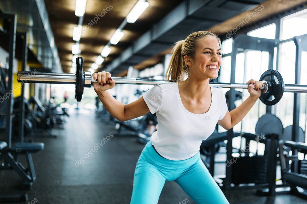 Beautiful active woman doing squats in gym