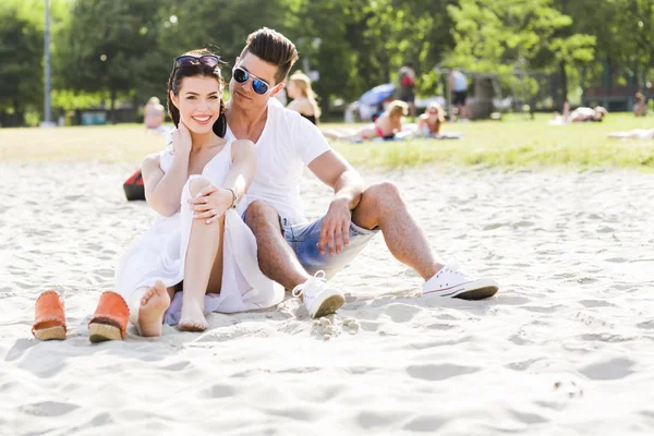 Romantische jonge paar zittend op een strand — Stockfoto