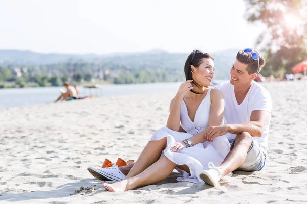 ロマンチックな若いカップルはビーチで座っています。 — ストック写真