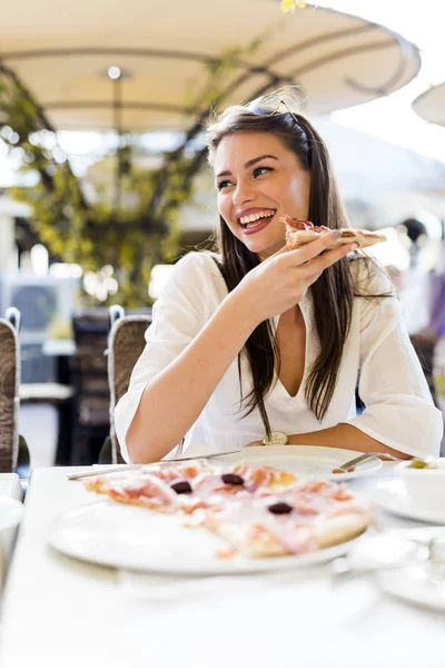 Bella giovane donna che mangia una fetta di pizza in un ristorante — Foto Stock