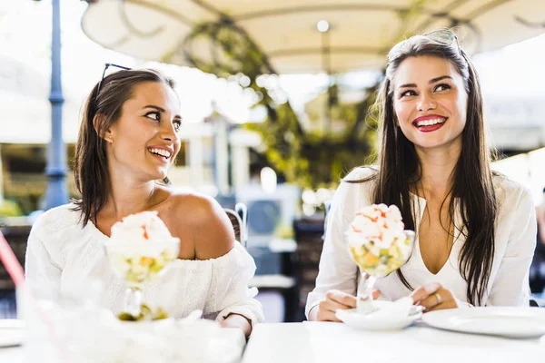 Two beautiful young women smiling and having a fruit salad in a — Stock Photo, Image