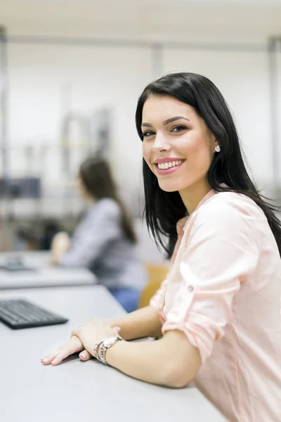 Ung vacker kvinna som ler lyckligt i ett klassrum — Stockfoto