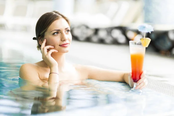 Schöne junge Frau trinkt einen Cocktail beim Schwimmen — Stockfoto