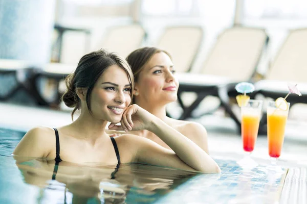Vackra unga kvinnor dricker en cocktails i poolen — Stockfoto
