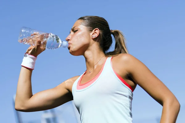 Junge schöne Athletin trinkt Wasser nach dem Training — Stockfoto