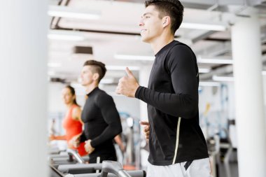 bir spor salonunda koşu bandı kullanan kişiler