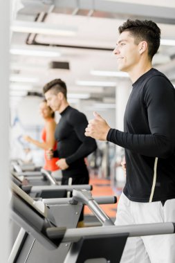 bir spor salonunda koşu bandı kullanan kişiler
