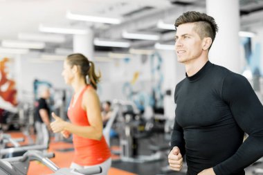 bir spor salonunda koşu bandı kullanan kişiler