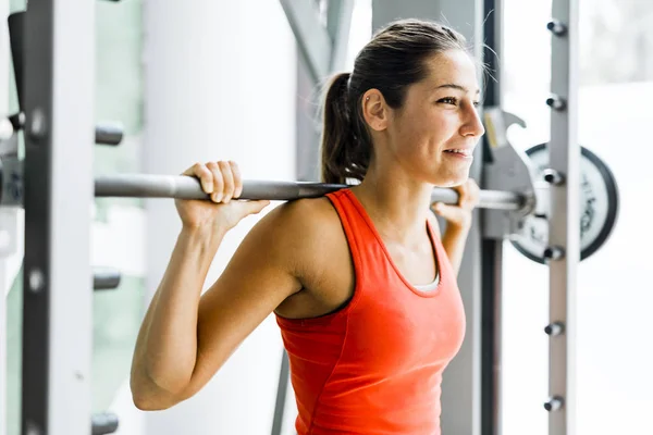 Femme soulevant des poids dans une salle de gym — Photo