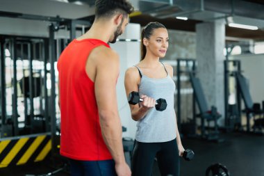 Spor salonunda antrenör ile çalışma dışarı genç yetişkin kadın