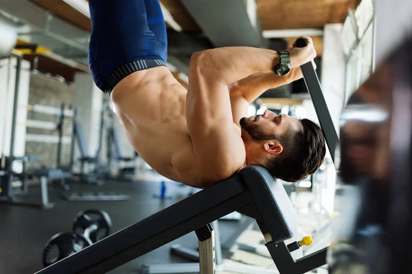 Joven hombre guapo haciendo ejercicio para los músculos abdominales —  Fotos de Stock