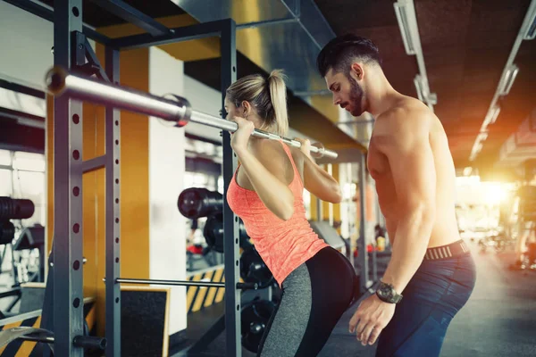 Mulher fazendo agachamentos com seu personal trainer — Fotografia de Stock