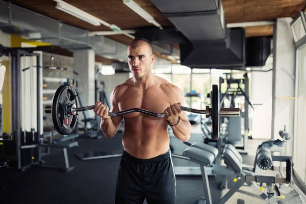 Gespierde bodybuilder training in de sportschool doen biceps oefeningen — Stockfoto