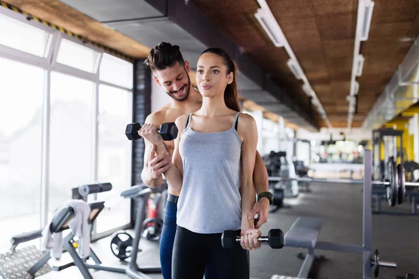 Jovem fazendo exercícios no ginásio com treinador — Fotografia de Stock