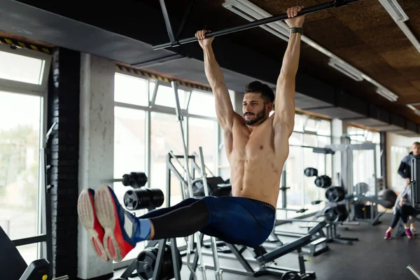 Jovem realizando pendurado perna levanta exercício — Fotografia de Stock