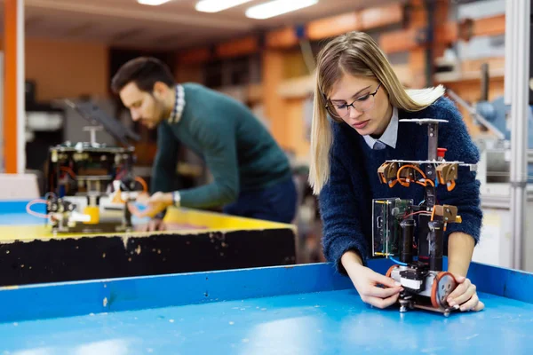 Young students of robotics preparing robot for testing — Stock Photo, Image