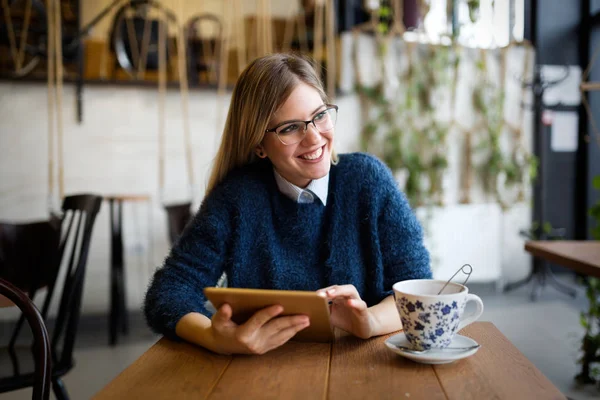 Gülümseyen genç kadın kahve dükkanında dijital tablet kullanma