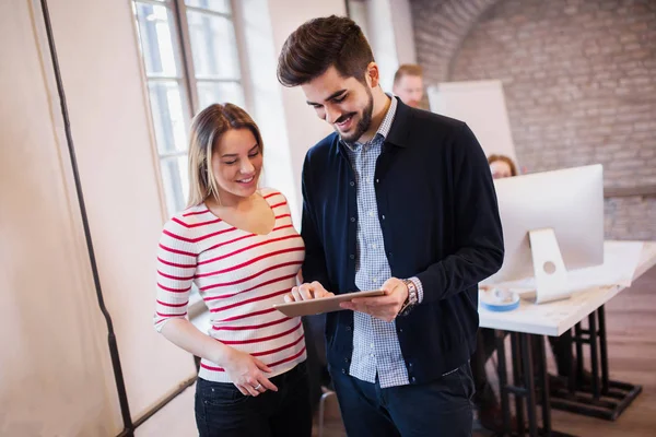 Young attractive designers talking and looking at digital tablet — Stock Photo, Image