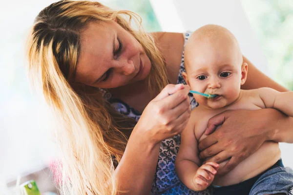 Retrato de la madre alimentando a su bebé con cuchara — Foto de Stock