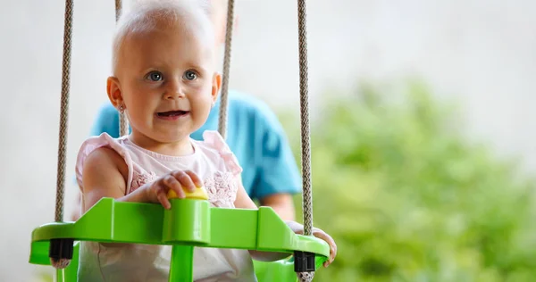 Bebé feliz disfrutando de actividades al aire libre y sonriendo mientras se balancea —  Fotos de Stock