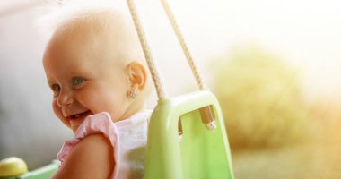 Mutlu neşeli bebek salıncak iken üzerinde gülümseyen