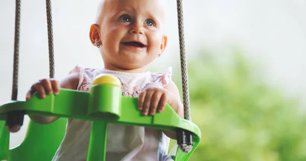 Bebé feliz disfrutando de actividades al aire libre y sonriendo mientras se balancea —  Fotos de Stock