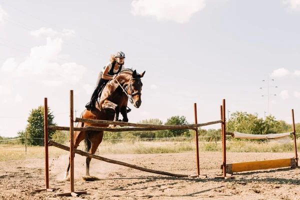 Jeune femme jockey sur cheval bondissant sur l'obstacle — Photo
