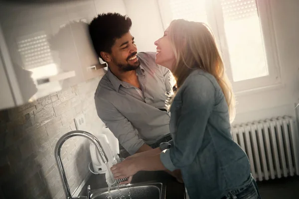 Νεαρό ζευγάρι κάνει πιάτα στην κουζίνα και να χαμογελά — Φωτογραφία Αρχείου