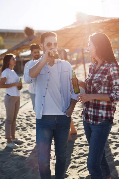 Счастливая пара улыбается и пьет пиво на пляже — стоковое фото