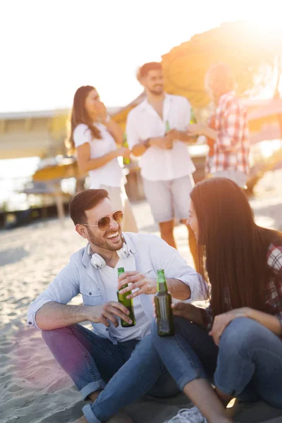 幸せなカップルの笑顔やビーチでビールを飲む — ストック写真