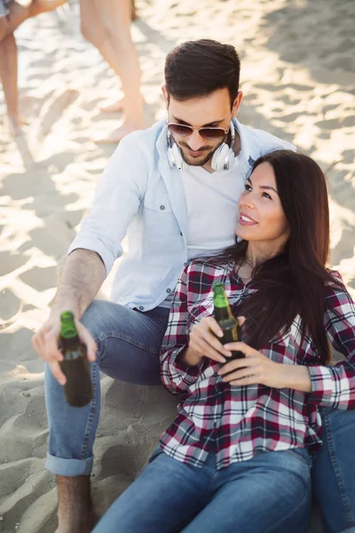 幸せなカップルの笑顔やビーチでビールを飲む — ストック写真