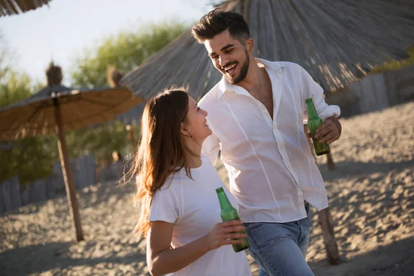 Heureux couple souriant et buvant de la bière à la plage — Photo