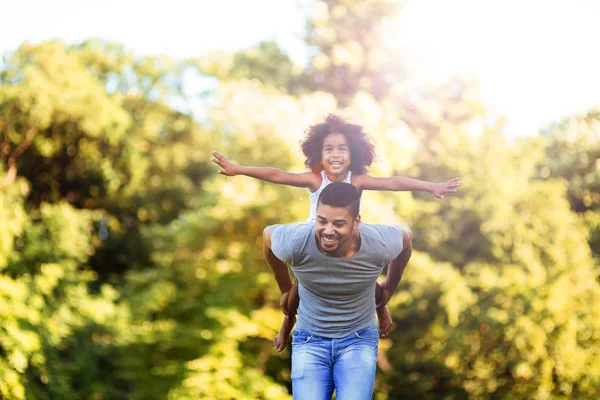 Retrato do jovem pai carregando sua filha de costas — Fotografia de Stock