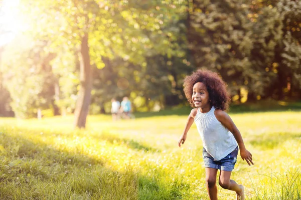 Porträtt av glad liten flicka kör på gräs mark — Stockfoto