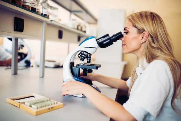 Jovem cientista olhando através do microscópio em laboratório — Fotografia de Stock