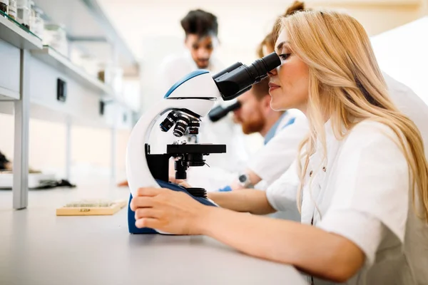 Jovem cientista olhando através do microscópio em laboratório — Fotografia de Stock