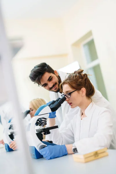 Ung forskare tittar genom mikroskopet i laboratorium — Stockfoto