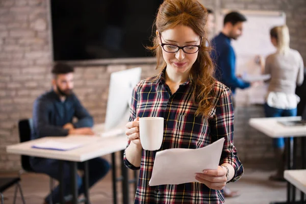 Retrato de jovem designer feminino bonito segurando xícara de café e — Fotografia de Stock