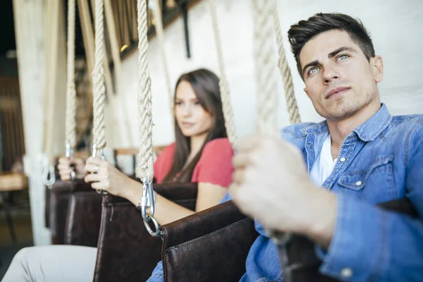 Retrato de casal sentado em baloiços — Fotografia de Stock