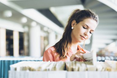 Raf bir kitaplıktaki bir kitap seçerek kadın