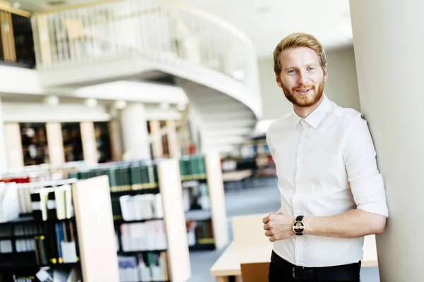 Beau étudiant souriant dans la bibliothèque — Photo