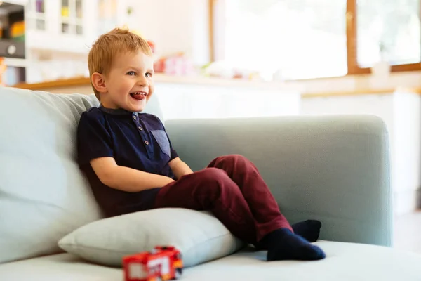 Счастливый мальчик сидит на диване в гостиной — стоковое фото