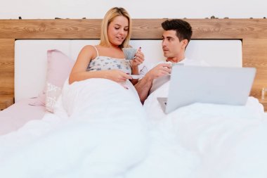 Çift yatakta kahve ve dizüstü bilgisayar ile