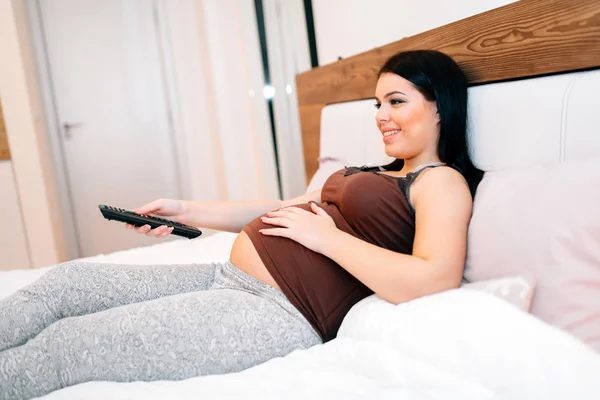 Zwangere vrouw tv kijken — Stockfoto