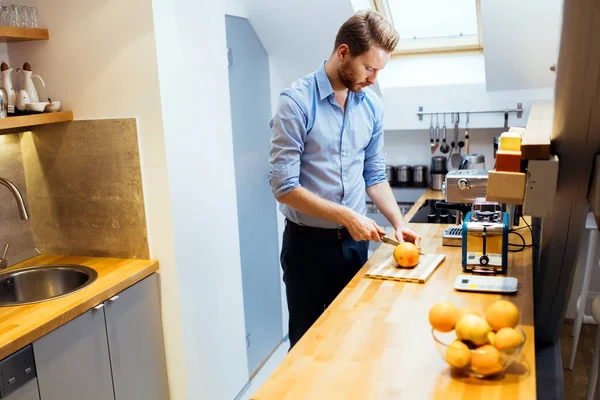 Mann schneidet Orangen in Küche — Stockfoto