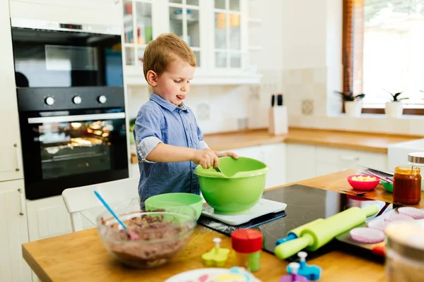 Ребенок помогает матери делать кексы — стоковое фото